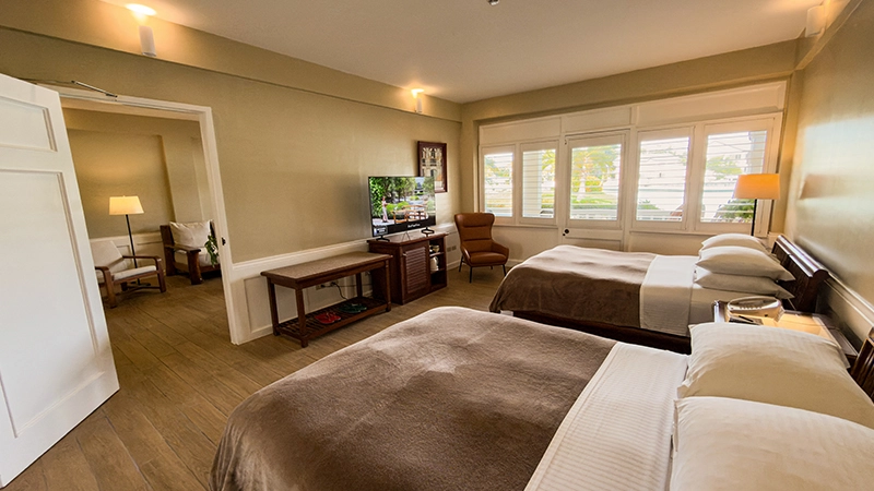 Beachside One-Bedroom Suite bedroom with two beds facing a wall-mounted TV