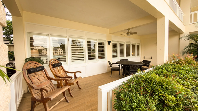 Beachside One-Bedroom Suite covered veranda with rocking chairs and wicker dining set