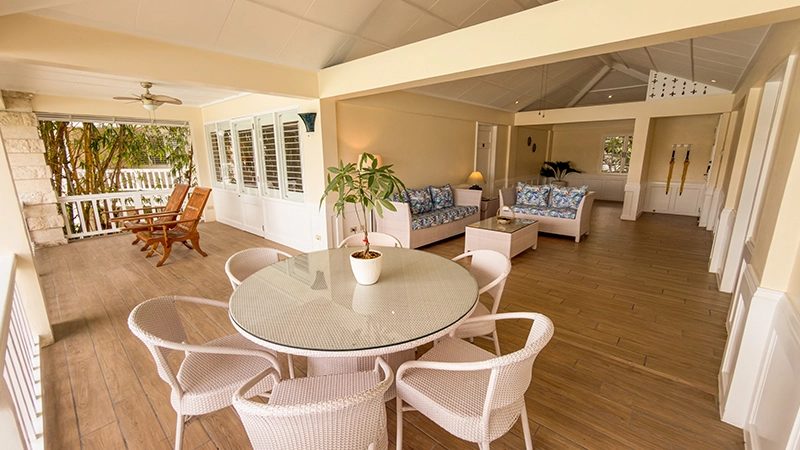 Beachside Two-Bedroom Suite open-plan dining table with wicker sofas in the living area beyond
