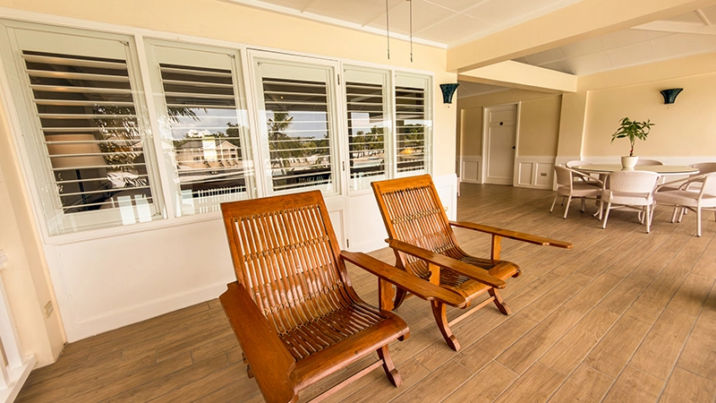Beachside Two-Bedroom Suite plantation lounge chairs beside louvered windows overlooking the lagoon