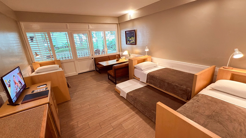 Fourplex Room with four single beds, TV console, and window banquette