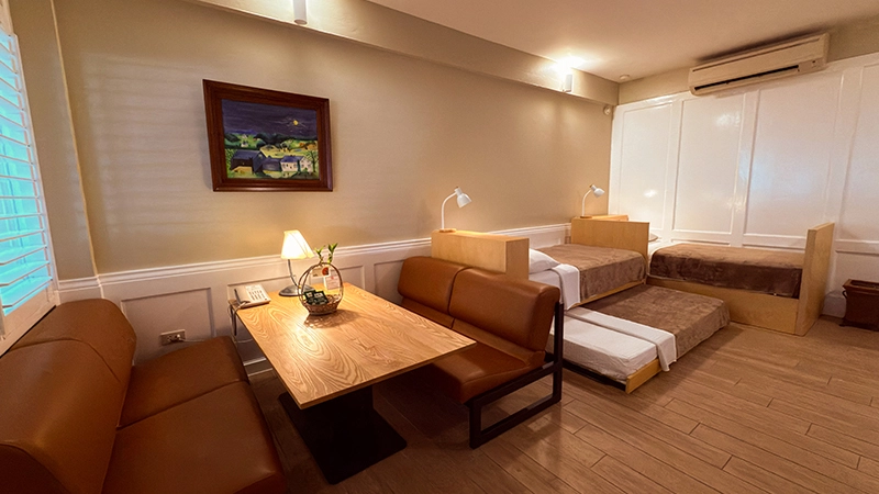 Fourplex Room lounge and work table with the four single beds beyond