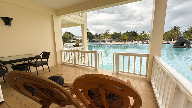 Water's Edge Room private balcony with lounge chairs and a step-down gate directly into the saltwater lagoon