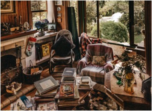 Cluttered living room crowded with furniture and piles of books