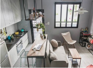Cramped studio apartment with kitchen, sofa, and desk in one room