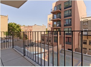 Small city balcony behind railings, facing apartment blocks