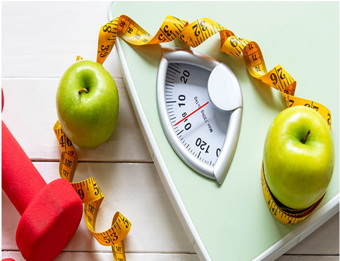 Weighing scale with green apples, a tape measure, and a dumbbell